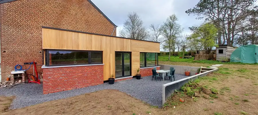 Annexe au bardage en bois et soubassement en briques rouges, terrasse en gravier devant