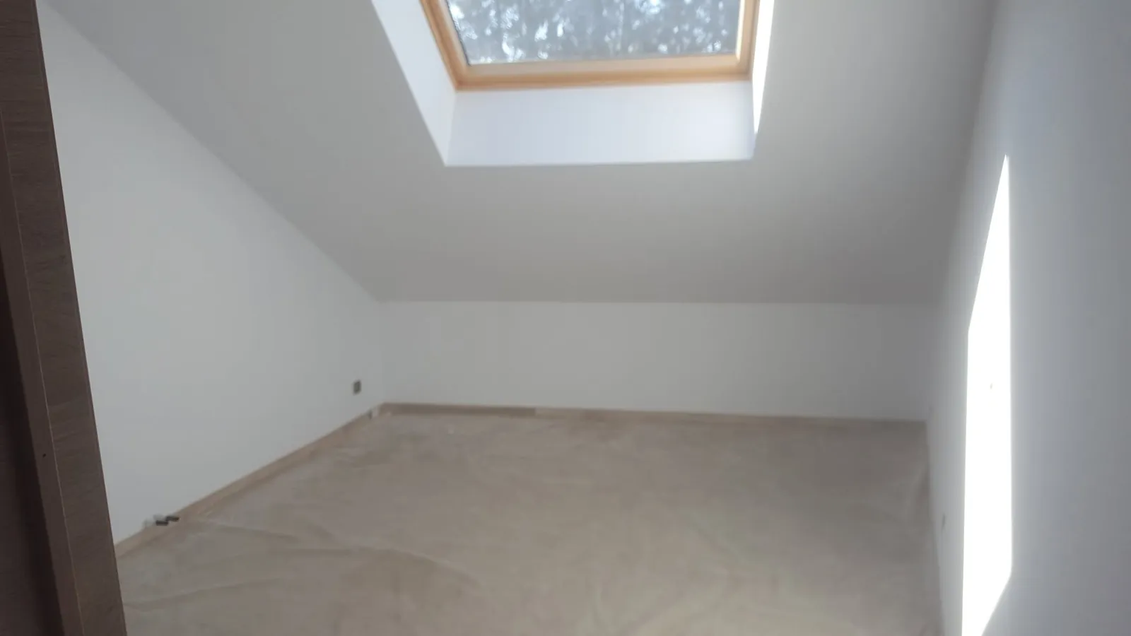 Pièce sous combles aux murs blancs avec une fenêtre de toit