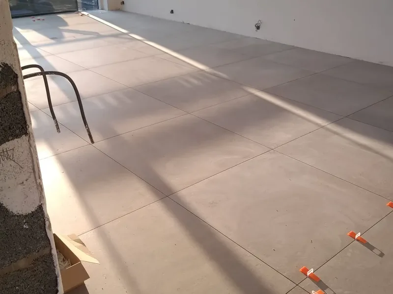 Long sol en grands carreaux gris dans une pièce lumineuse, croisillons orange entre les carreaux
