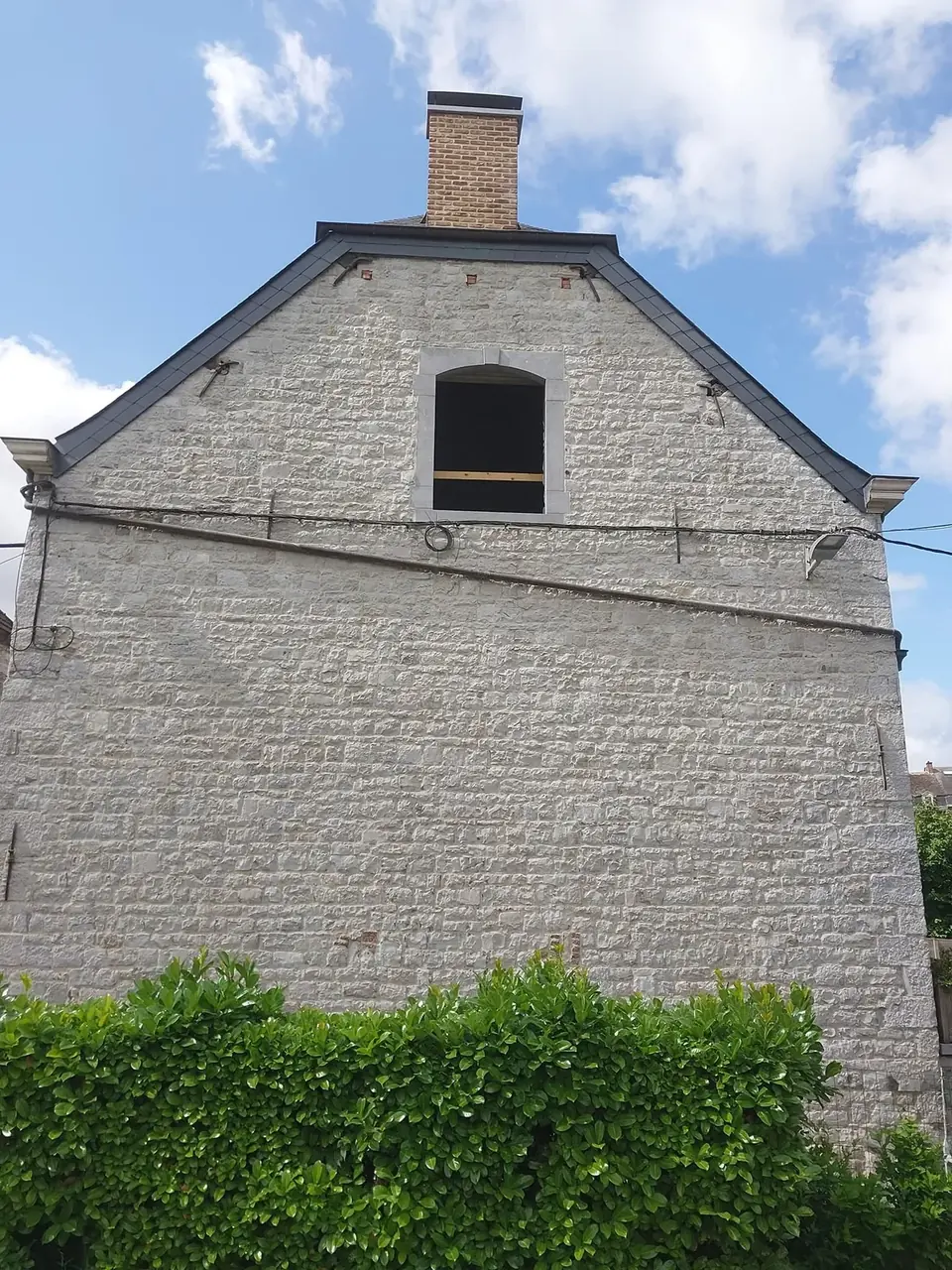 Pignon en moellons avec petite fenêtre cintrée