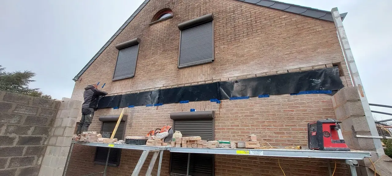 Façade en briques avec ouverture et poutre en cours de pose