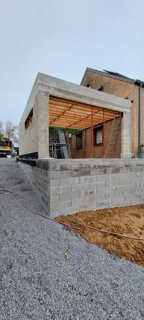 Annexe en blocs avec charpente de toiture contre la maison