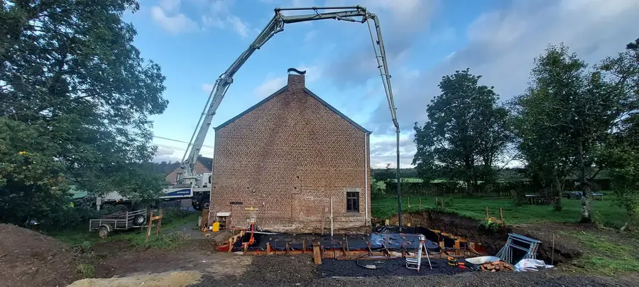 Camion-pompe qui coule la dalle derrière une maison en briques