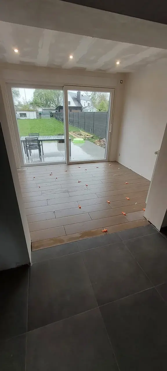 Pièce carrelée avec baie vitrée vers le jardin