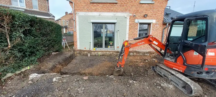 Mini-pelle dans l'ancien garage avant la construction