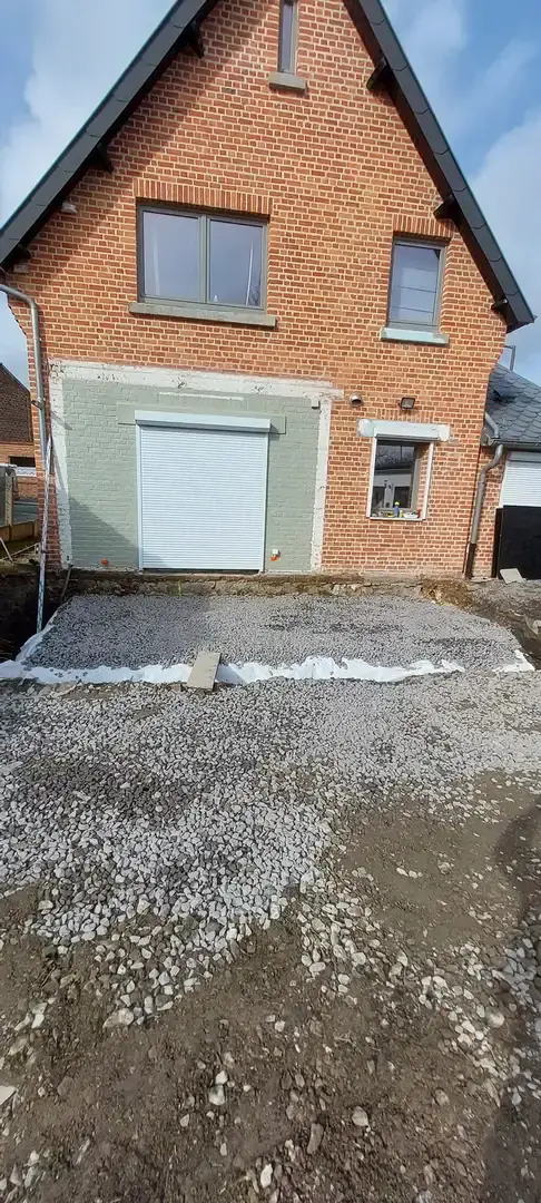 Façade de maison en briques avec porte de garage avant les travaux