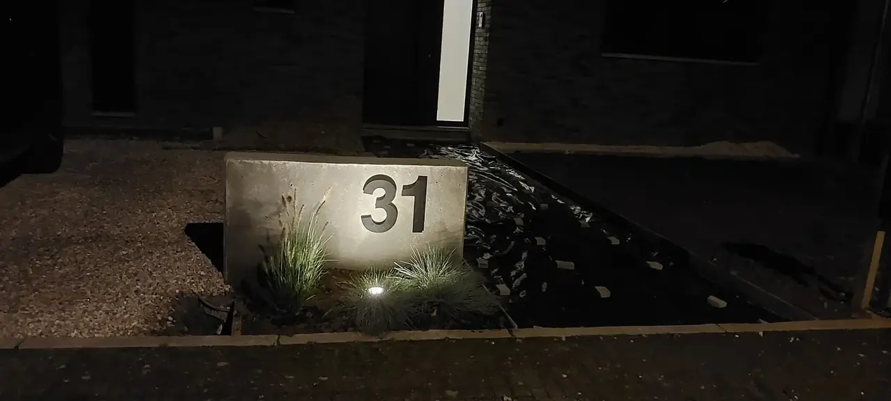 Numéro de maison éclairé la nuit sur un muret