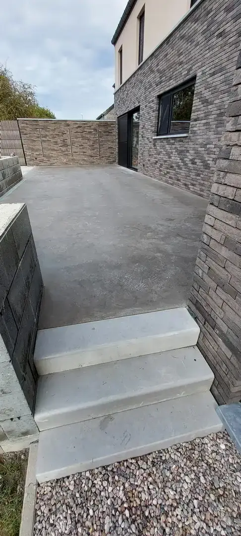 Escalier en béton lissé et terrasse devant la façade en briques