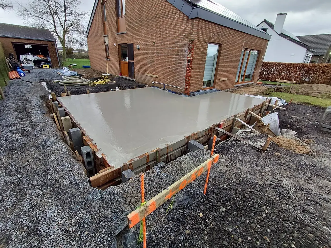Coffrage et dalle de béton le long de la maison en briques