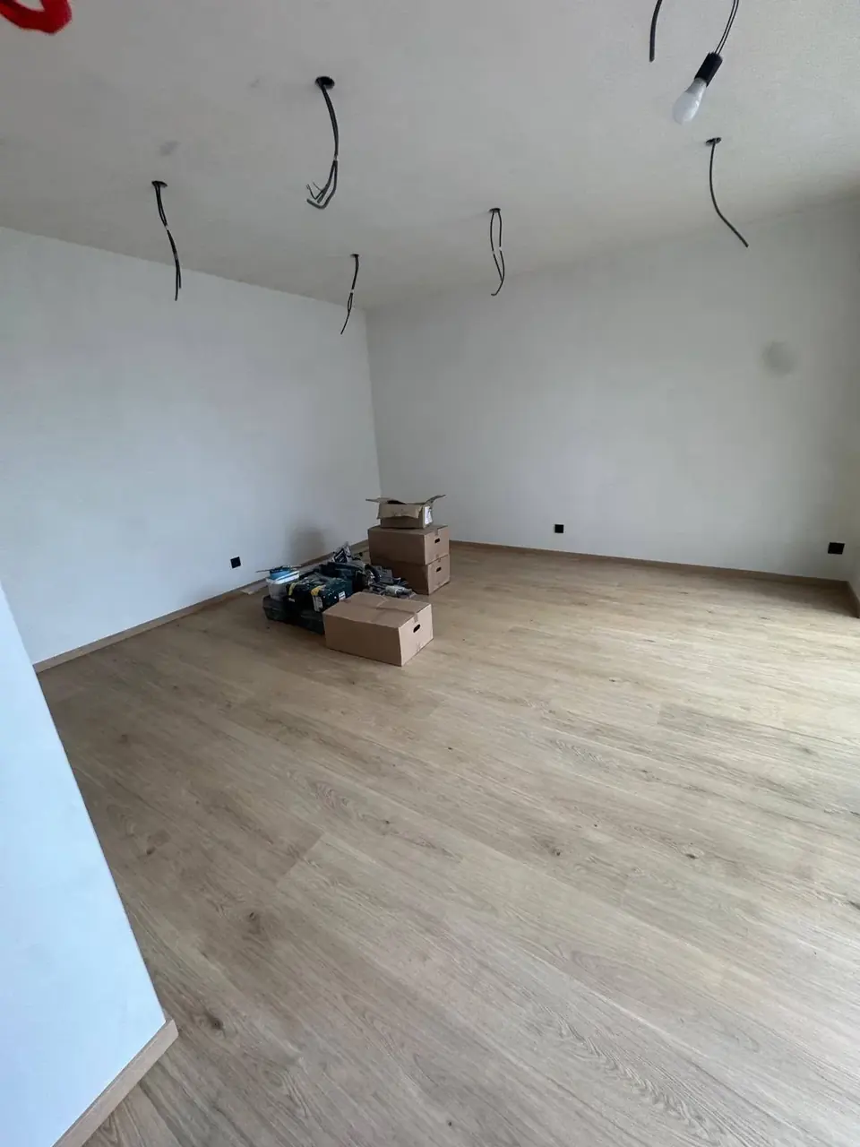 Pièce vide avec parquet clair et fils électriques en attente