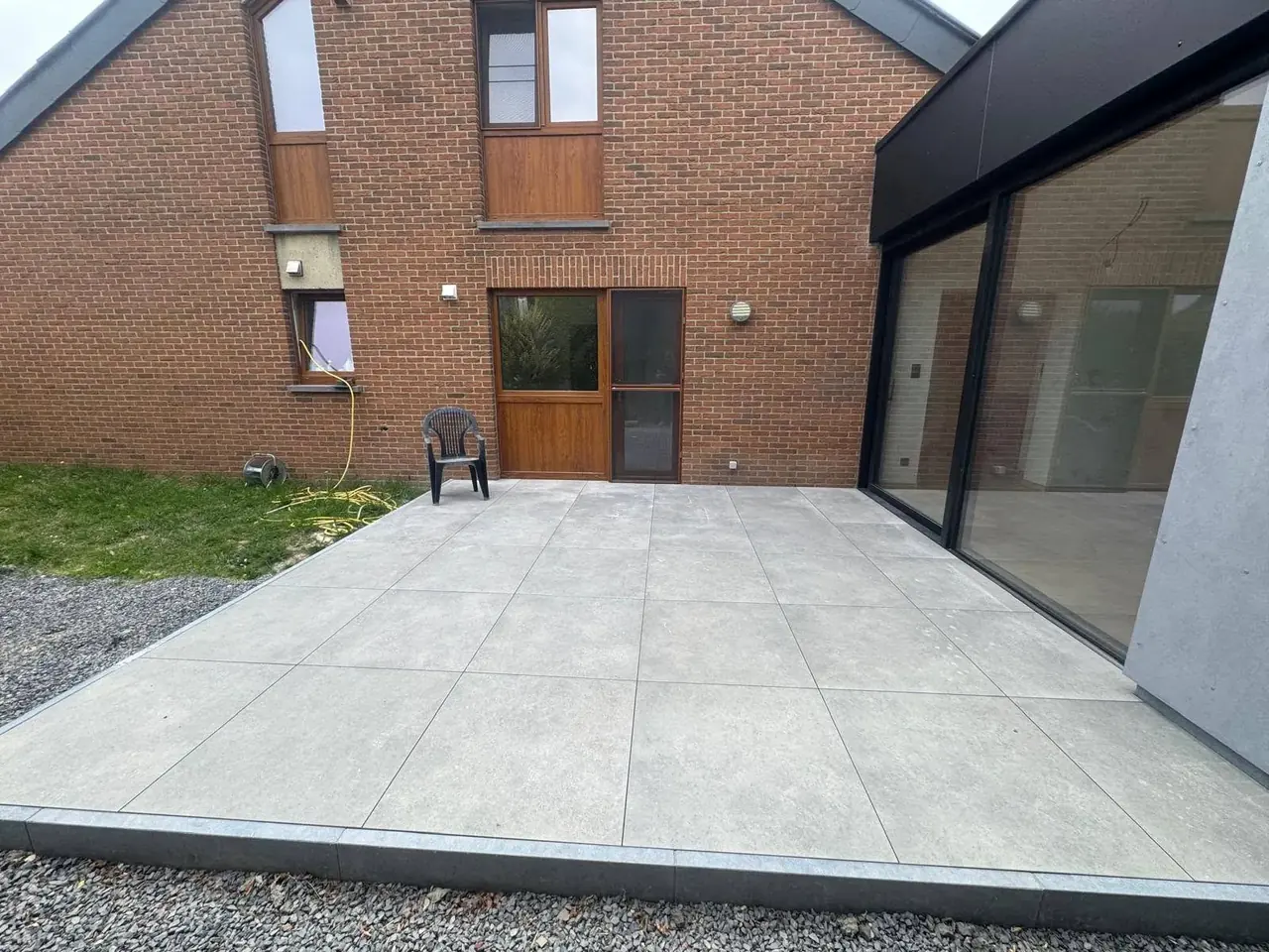 Grande terrasse en dalles devant l'extension et la maison en briques