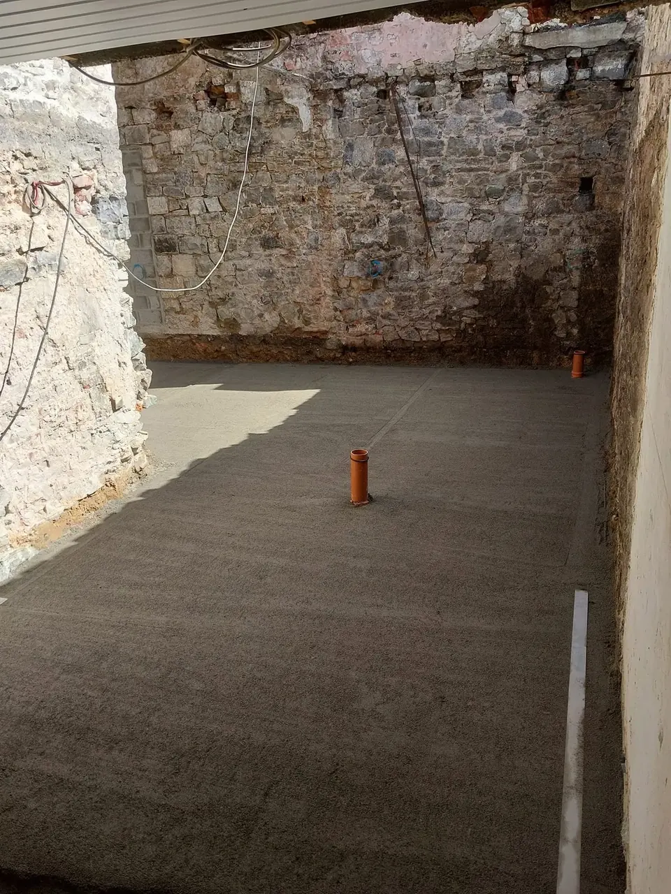 Dalle de béton brut dans une pièce voûtée en pierre