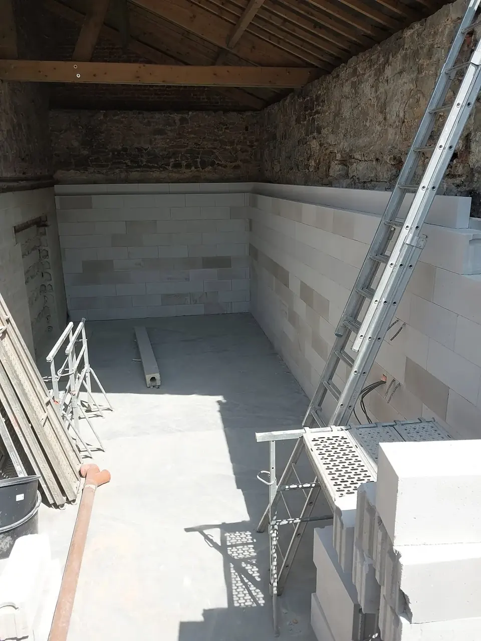 Pièce aux murs de béton cellulaire sous une charpente en bois