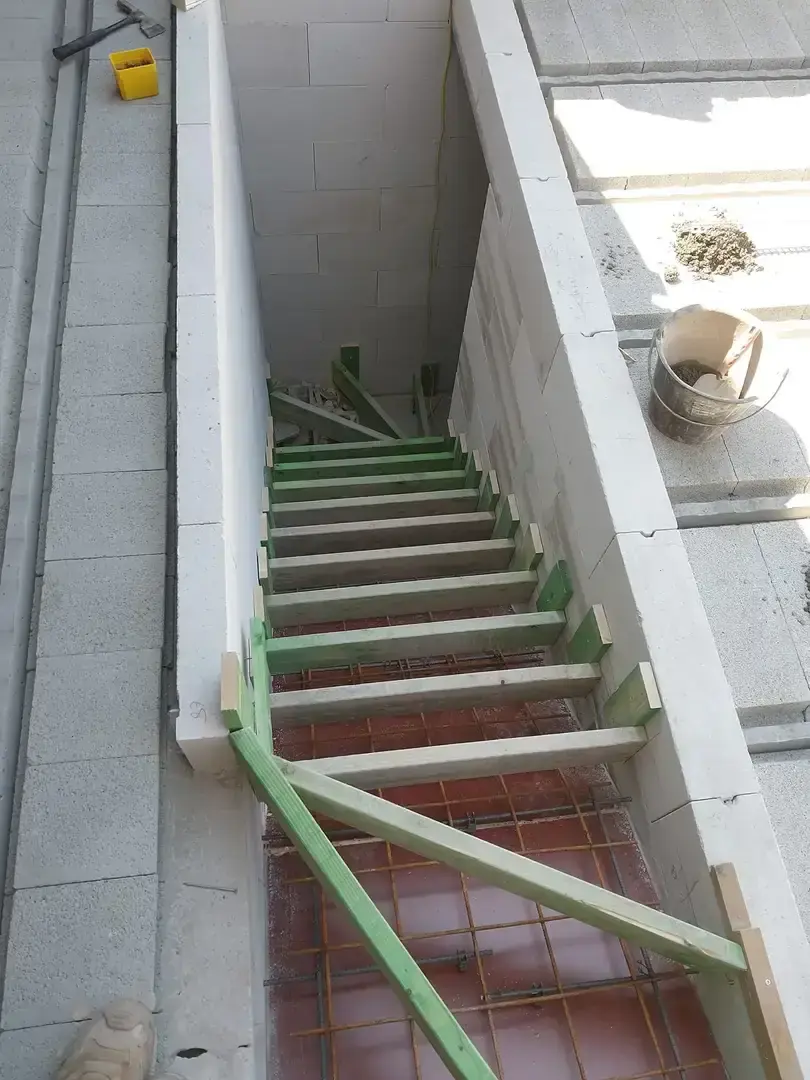 Escalier en cours de ferraillage entre des murs de blocs