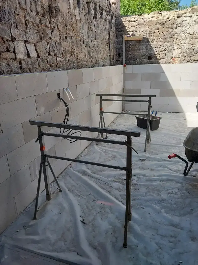 Mur en blocs de béton cellulaire contre un mur de pierre