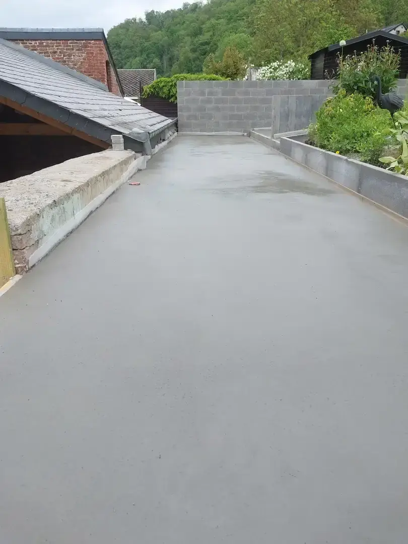 Dalle de béton lissée sur une terrasse étroite entre toiture et jardin