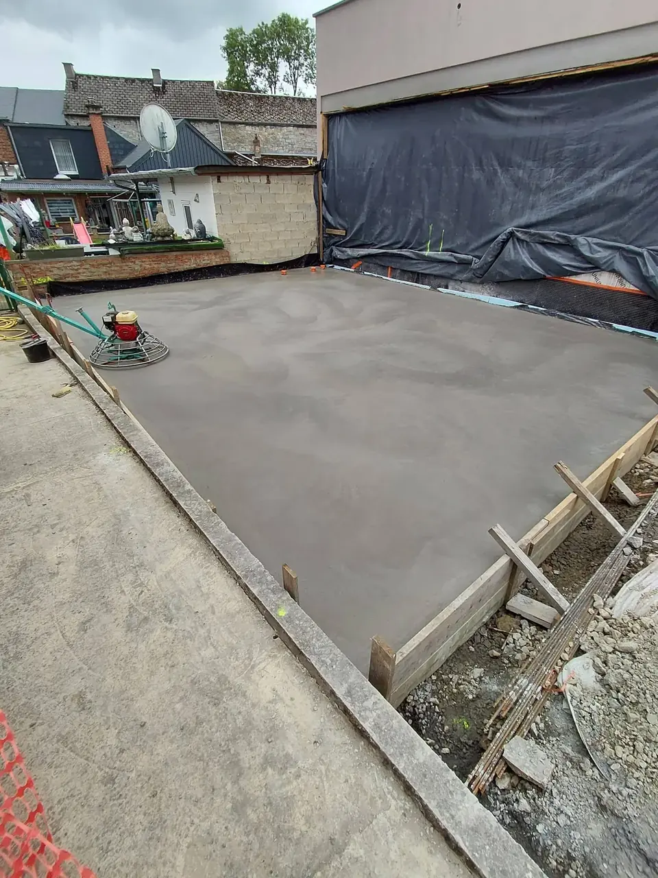 Dalle de béton lissée entre un coffrage et des bâches