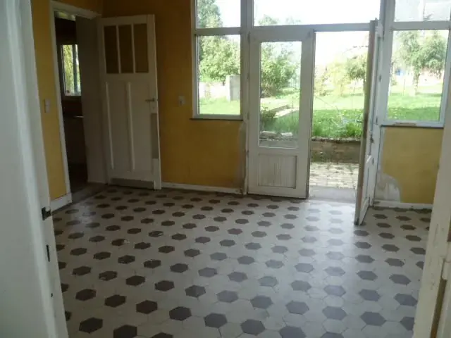 Séjour avec carreaux au sol et portes-fenêtres vers le jardin
