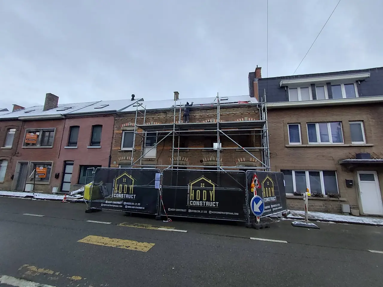 Maison en rénovation avec échafaudage et bâches de chantier sur la rue