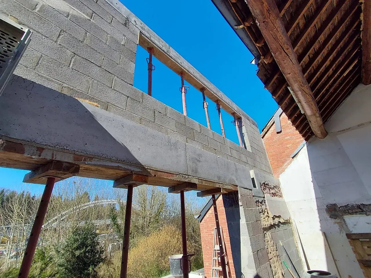 Mur en blocs sur poutre avec ciel bleu et toit en bois