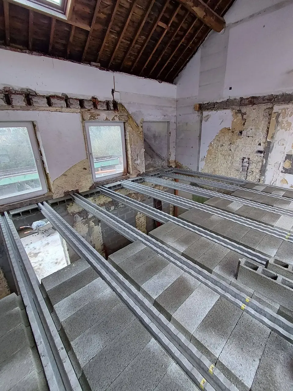 Hourdis et poutrelles posés dans une pièce avec fenêtres