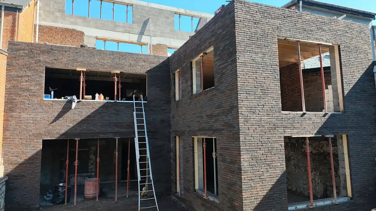 Maison avec façade en briques sombres et ouvertures