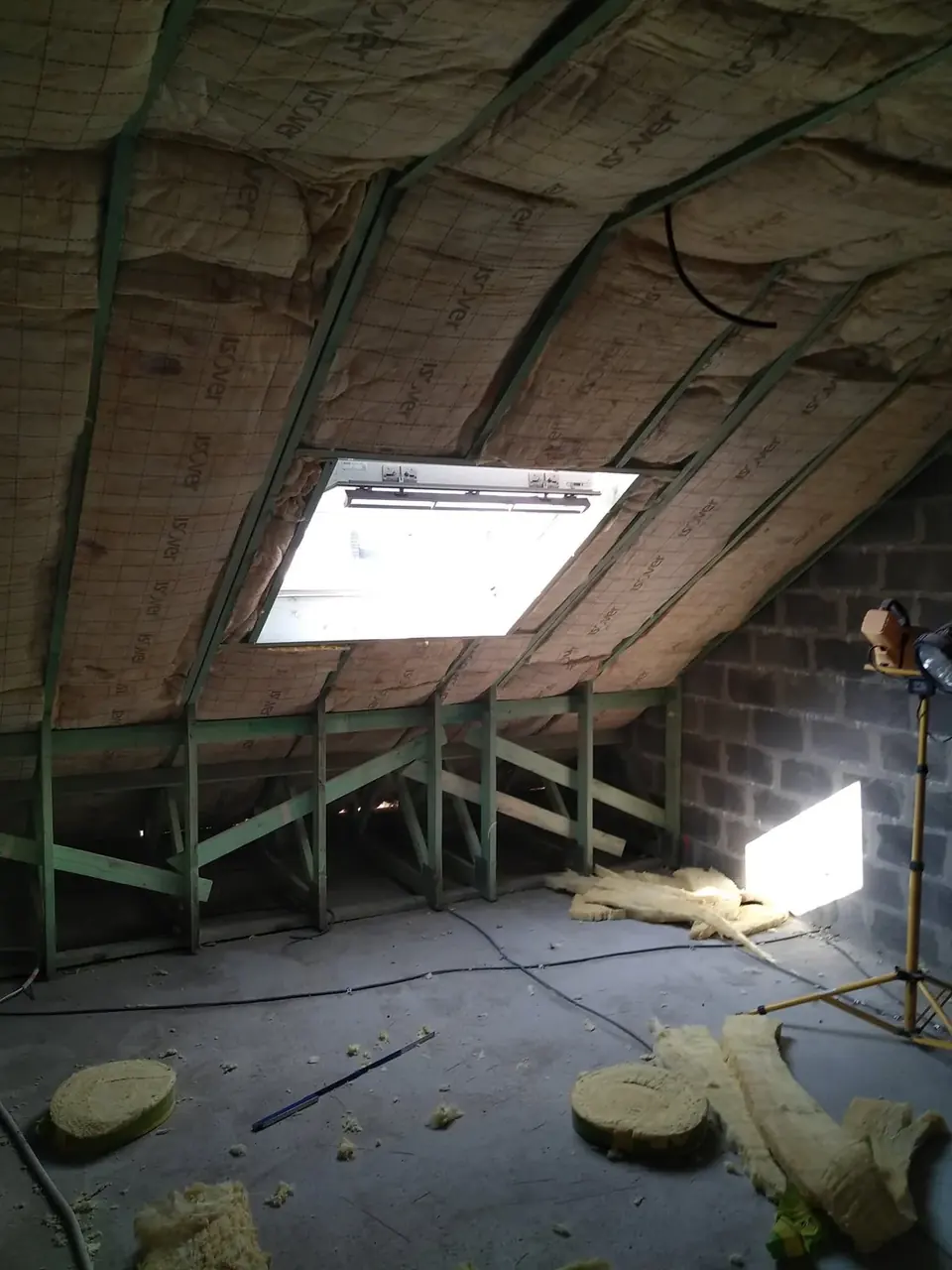 Combles avec isolant et fenêtre de toit, projecteur de chantier