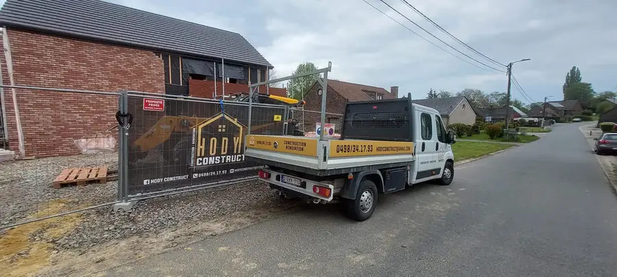 Façade en briques et camionnette de chantier avec bâche