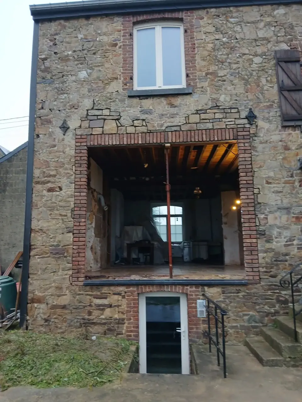 Façade en pierre avec grande ouverture agrandie et poutre