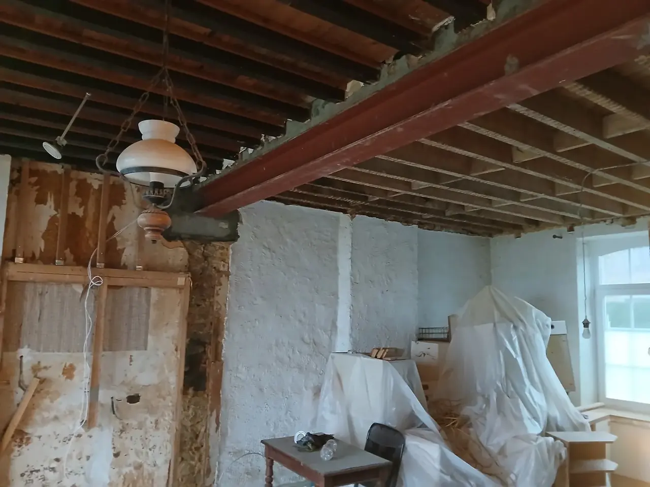 Plafond en solives avec poutre métallique rouge dans une pièce