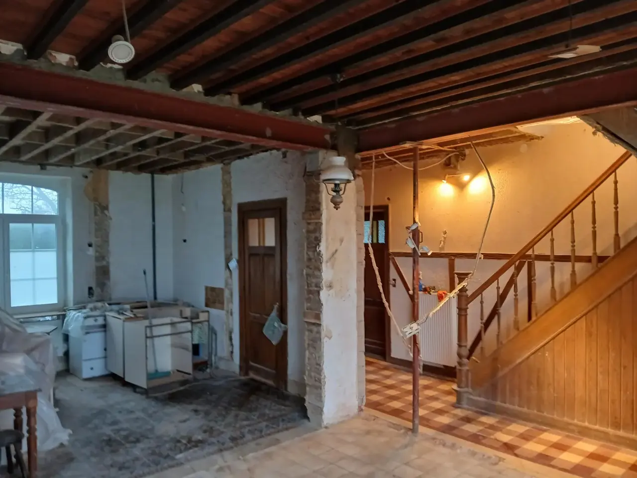 Pièce avec poutre métallique et escalier en bois à l'arrière