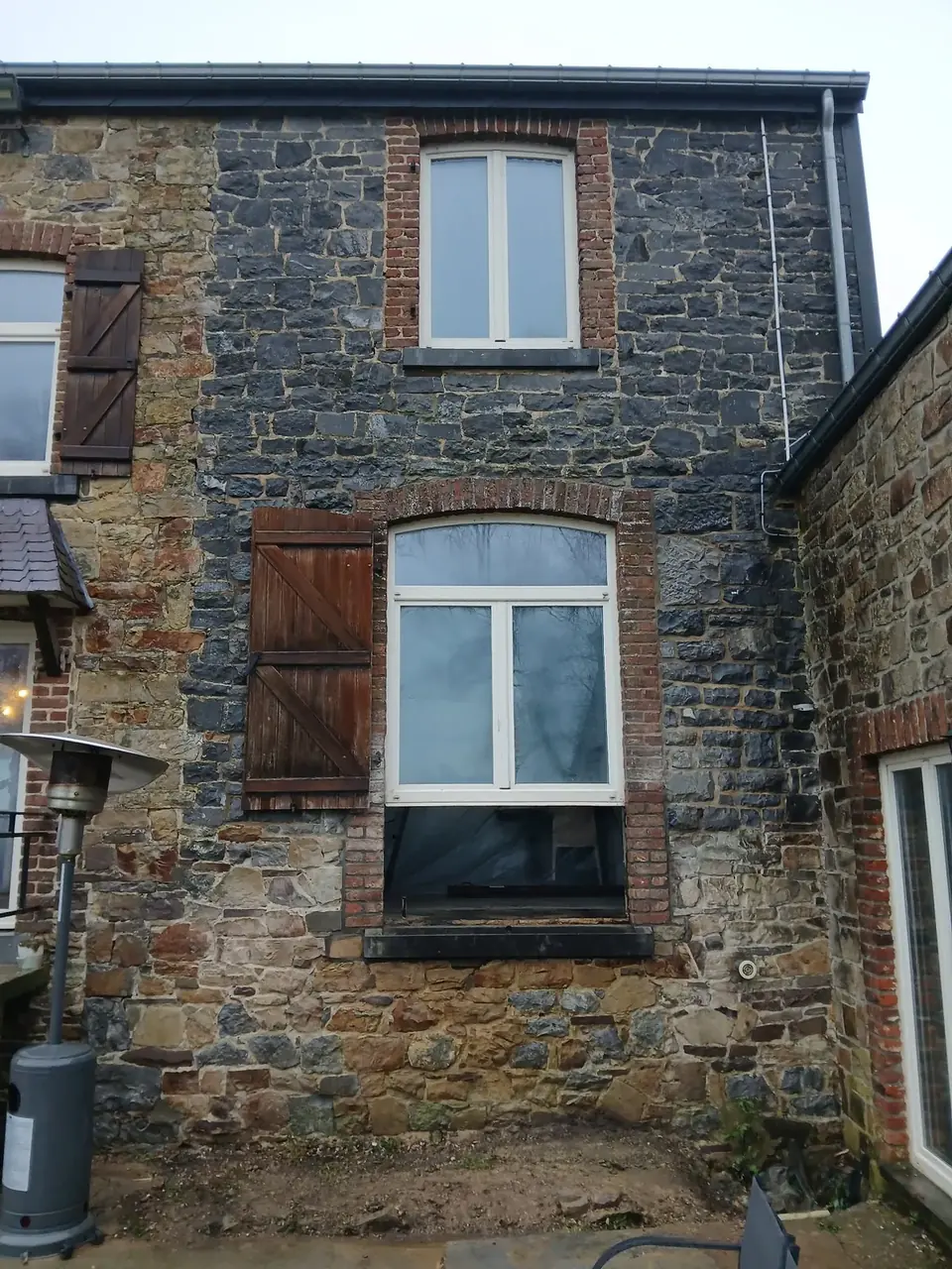 Façade en pierres avec fenêtre et volet