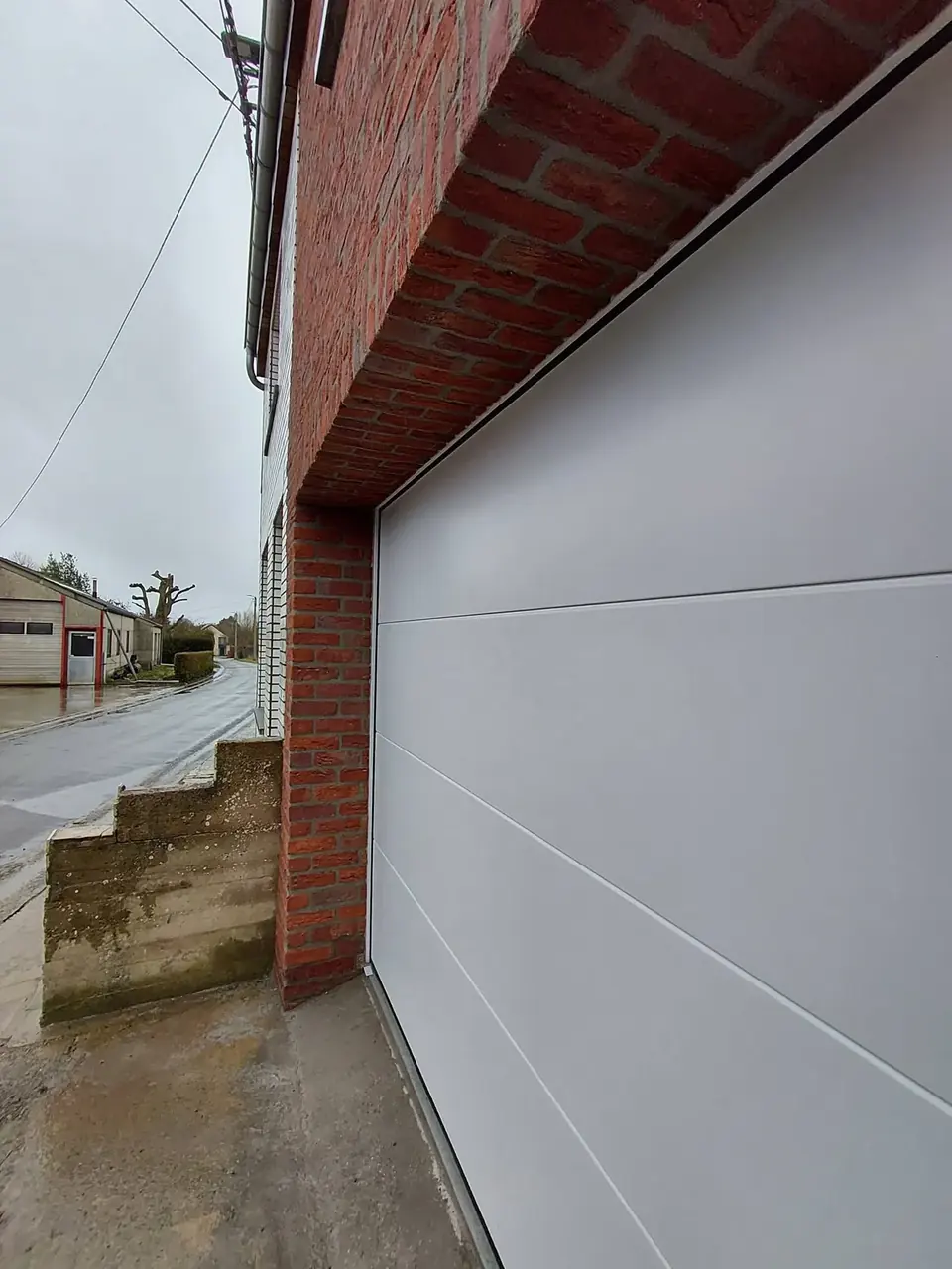 Porte de garage blanche sectionnelle dans un mur en briques