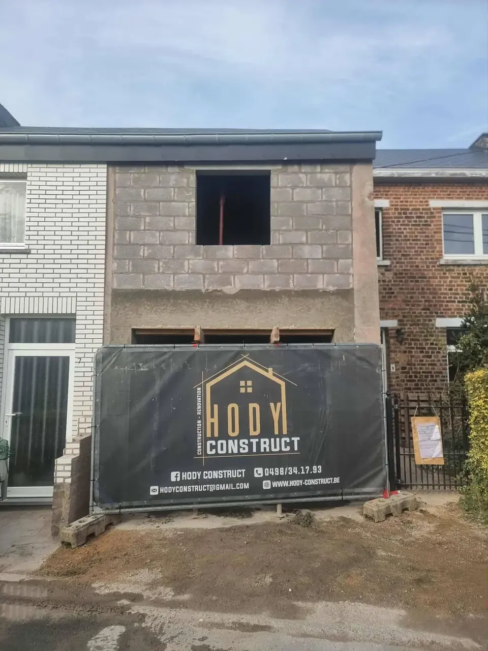 Façade en blocs avec bâche de chantier et ouverture haute
