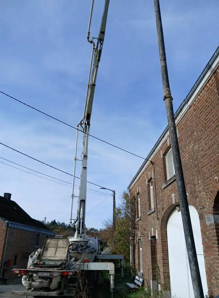 Camion-pompe qui coule la dalle devant le bâtiment en briques