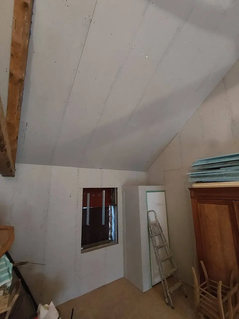 Pièce sous toiture avec plaques de plâtre et vieux meuble