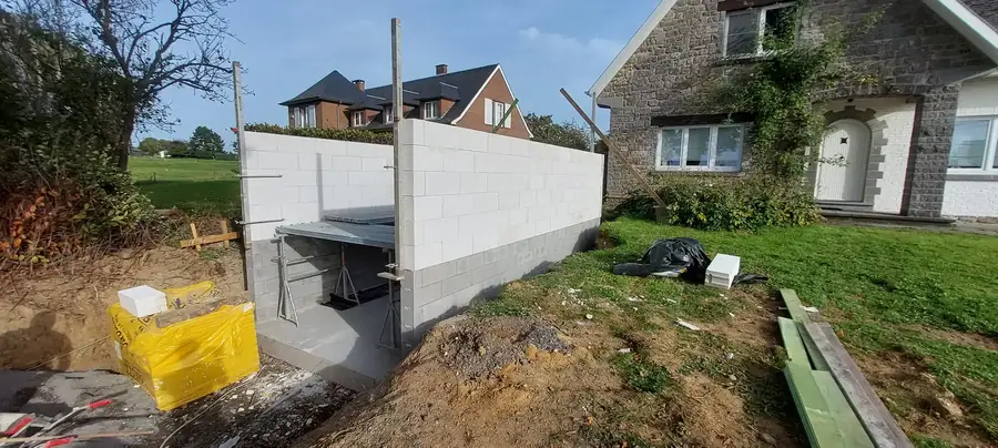 Murs en blocs du garage devant une maison en pierre