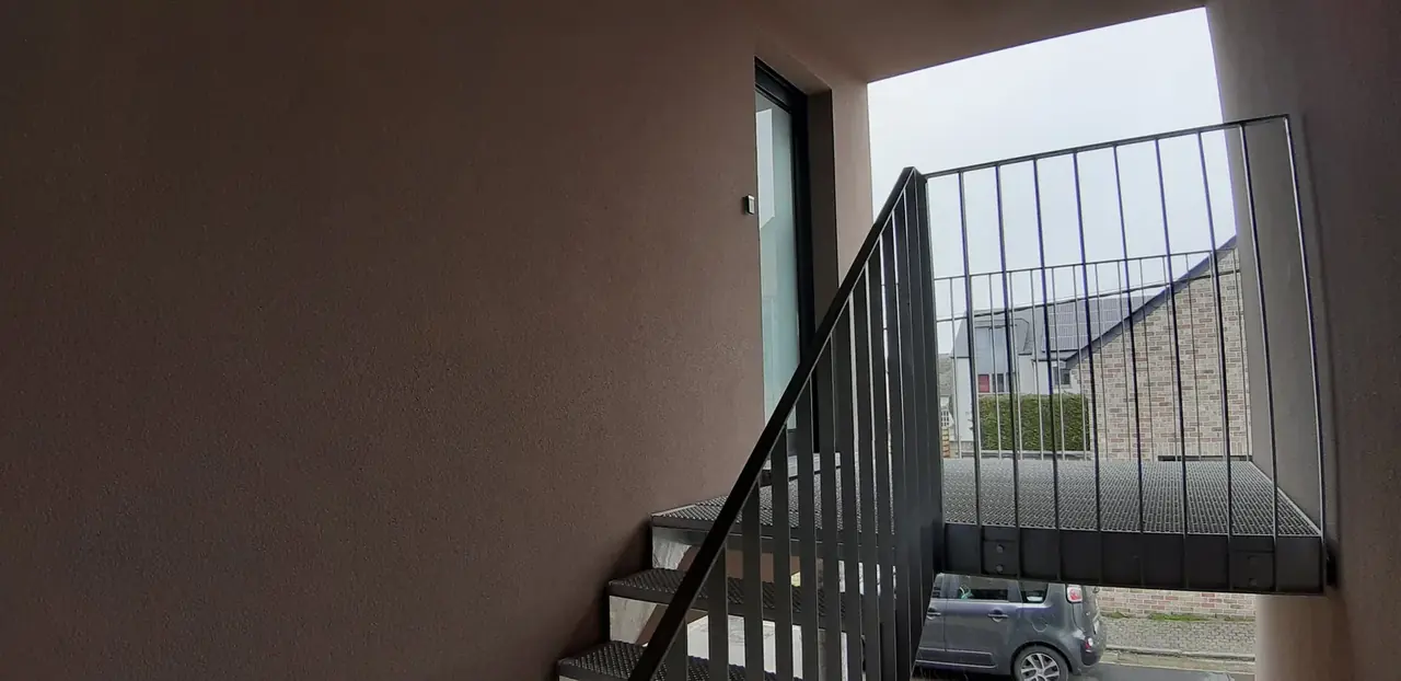Cage d'escalier avec garde-corps métallique et fenêtre