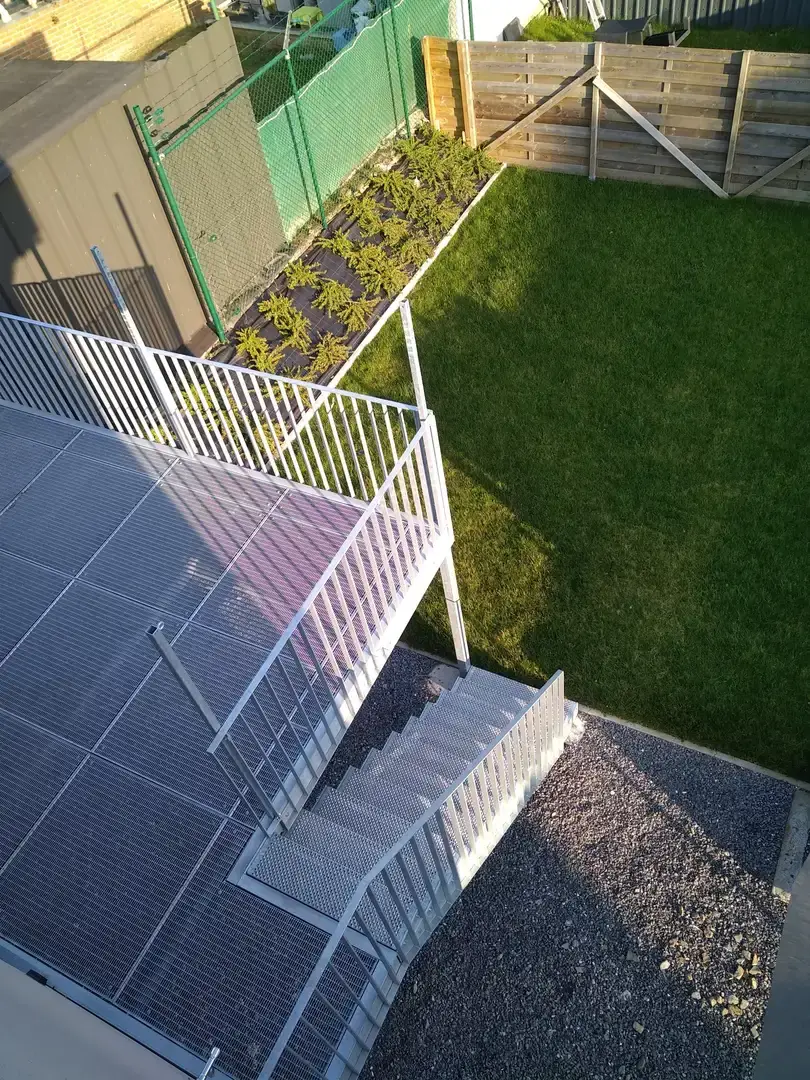 Jardin avec pelouse, terrasse et escalier extérieur métallique vus d'en haut