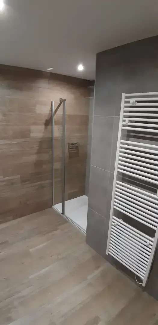Salle de douche carrelée avec radiateur sèche-serviettes