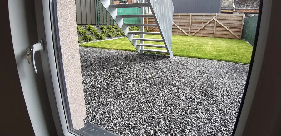 Vue depuis une fenêtre sur le jardin et l'escalier extérieur