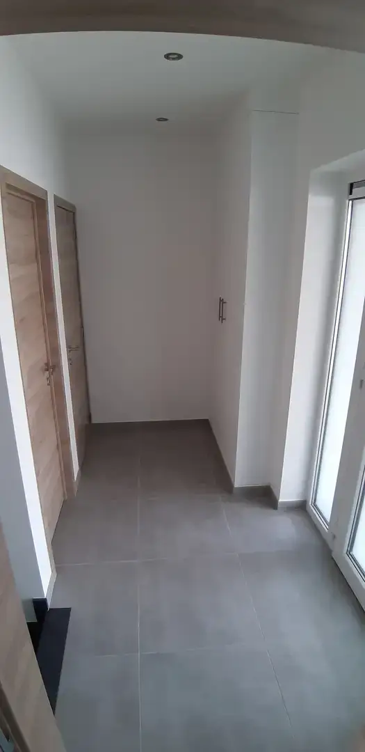 Couloir carrelé avec porte en bois