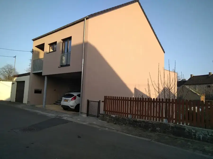 Immeuble enduit rose vu de la rue, carport au rez-de-chaussée