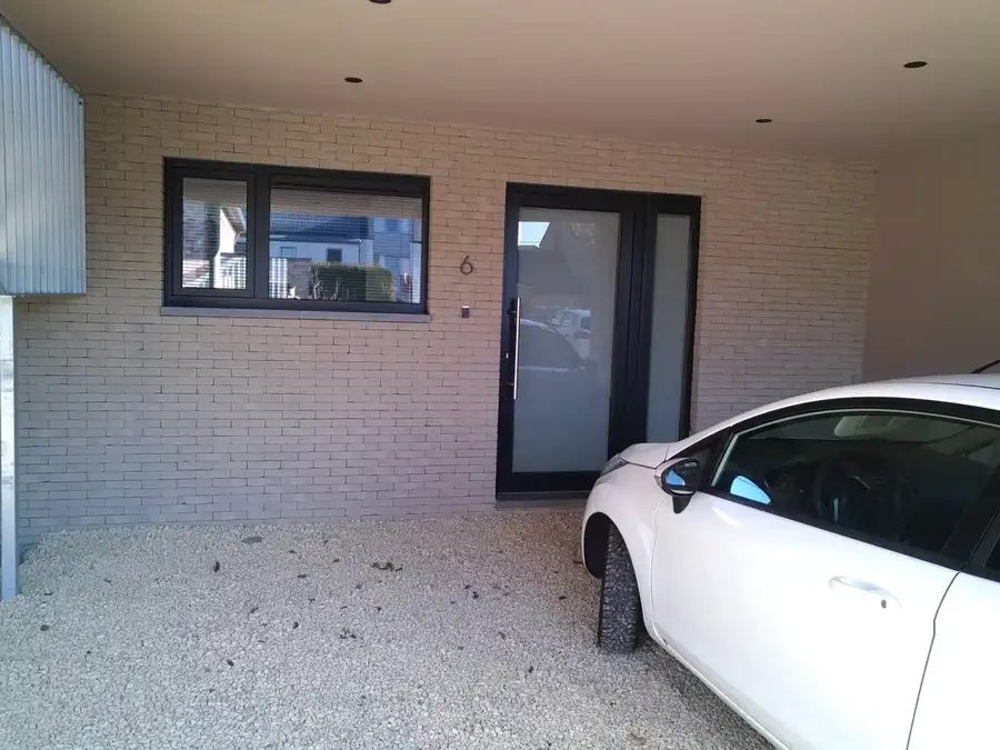 Entrée au rez-de-chaussée avec briques blanches, voiture sous carport
