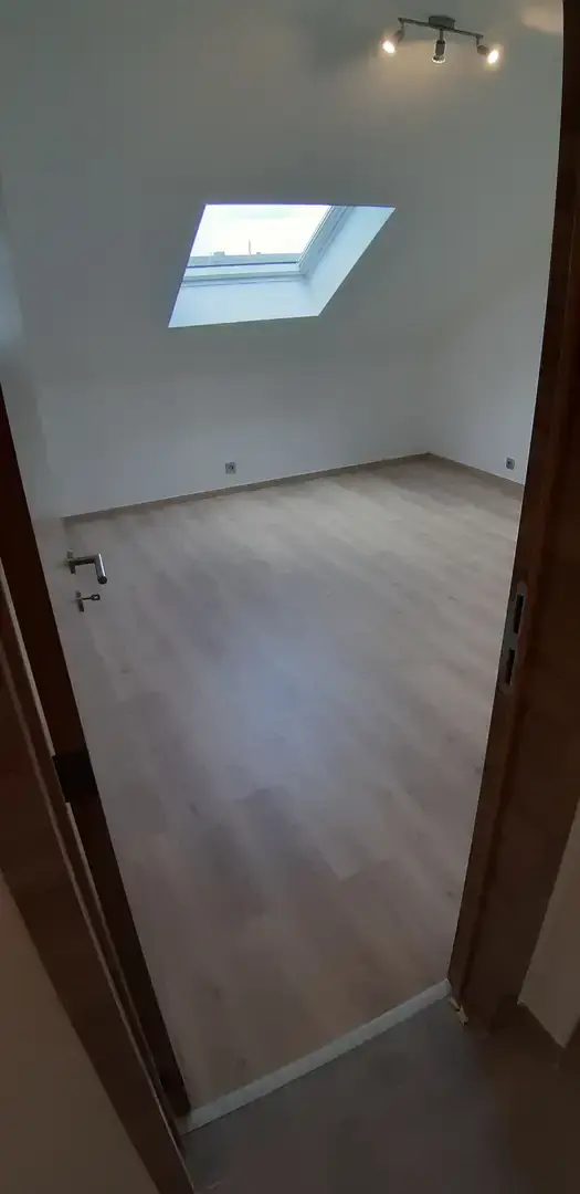 Chambre mansardée avec fenêtre de toit et parquet