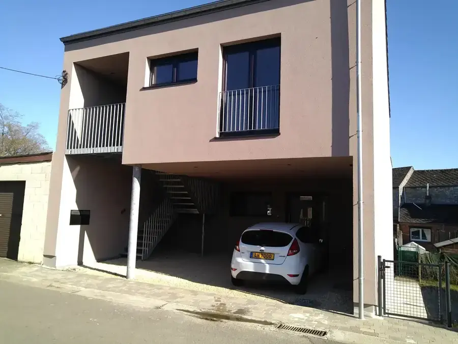 Façade enduite avec balcons et carport au rez-de-chaussée