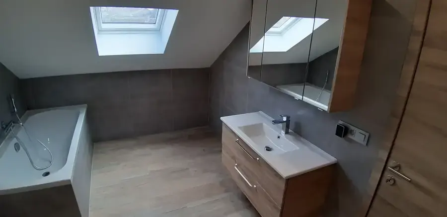 Salle de bain avec baignoire, vasque en bois et fenêtre de toit