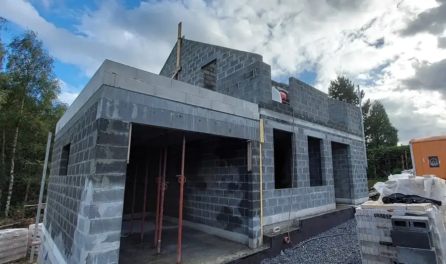 Maison en blocs avec grandes ouvertures et ciel nuageux