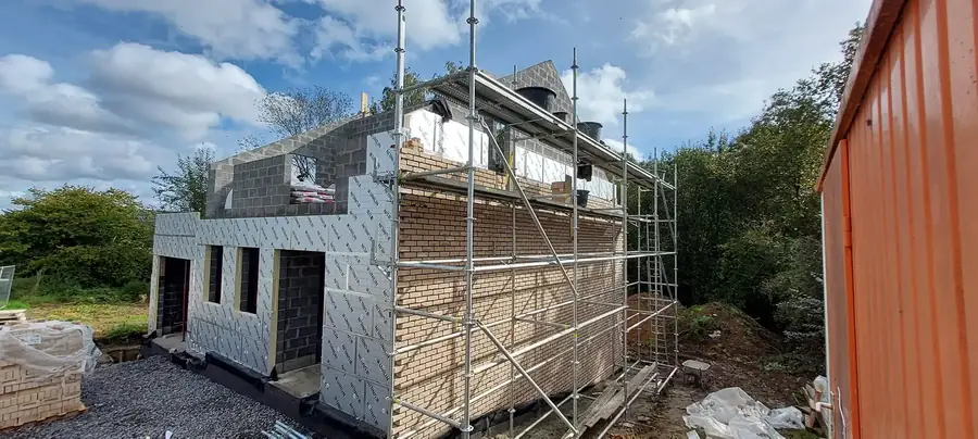 Maison avec isolant et échafaudage, vue sur les arbres