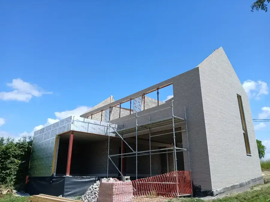 Maison en briques grises avec échafaudage et ciel dégagé